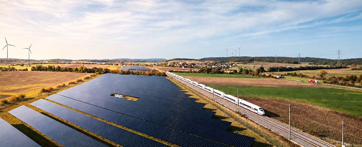 Gleise mit ICE, Bundesstraße mit Lastwagen neben einem großen Photovoltaik-Feld