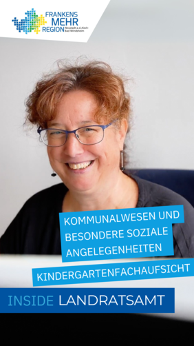Person mit lockigem Haar und Brille sitzt lächelnd vor einem Laptop.
