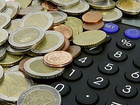 Geldmünzen liegen auf einem Taschenrechner