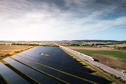 Photovoltaik an Bahnstrecke bei Markt Bibart mit ICE und Windkraft im Hintergrund
